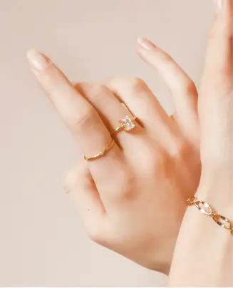 A woman 's hands with two rings on one finger.